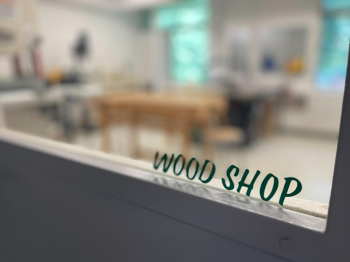 A sign reading Wood Shop on a blurred window