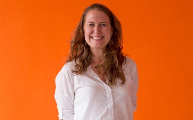 Arielle Sandor standing in front of an orange backdrop