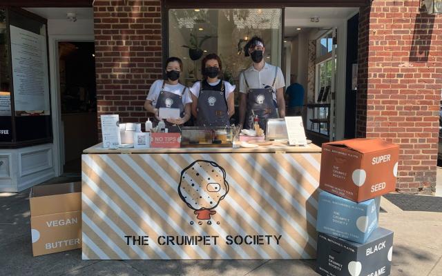 Entrepreneurial students selling crumpets at a table set up on the sidewalk.