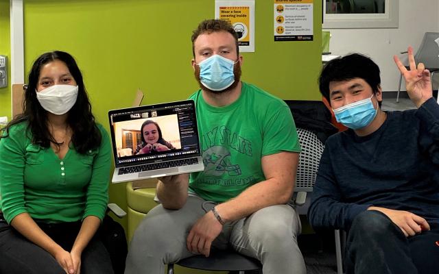 2 male students and 1 female student sitting with 1 female student on zoom