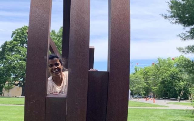 Smiling young woman peeking out from behind a sculpture