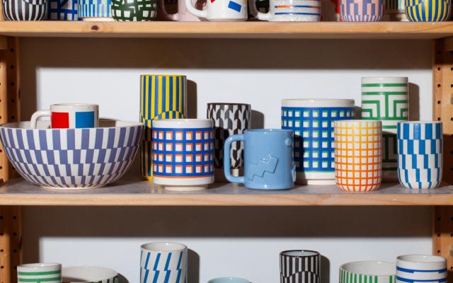 multiple shelves filled with colorful pottery mugs, bowls, vases