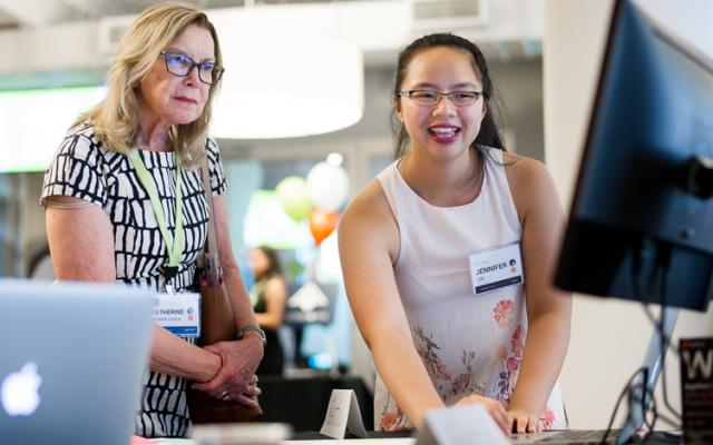 A student presenting their work on a computer to an attendee at eLab Demo Day