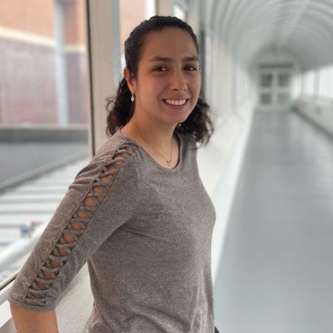 Franchesca smiling in an academic building corridor