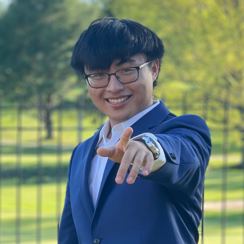 Confident student outside smiling and pointing towards camera