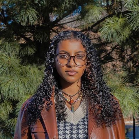 Student outside in front of wooded setting