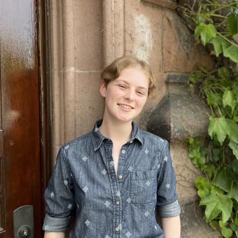 Student smiling outside in front of arch and ivy