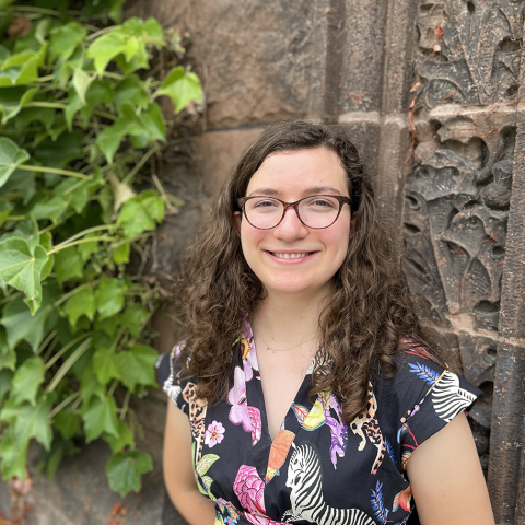 Smiling student standing in front of arch and ivy